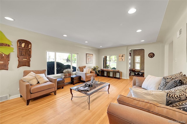 living area featuring arched walkways, light wood-style floors, recessed lighting, and baseboards