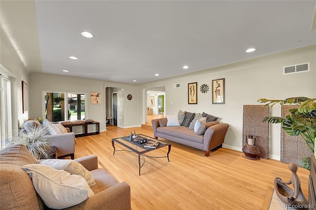 living area with arched walkways, light wood-style flooring, recessed lighting, and baseboards