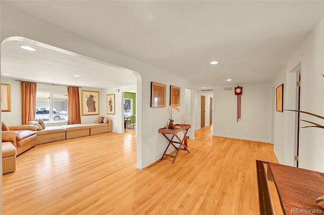 living room featuring arched walkways, light wood-style flooring, recessed lighting, and baseboards