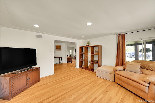 living room featuring arched walkways, light wood-style flooring, and recessed lighting