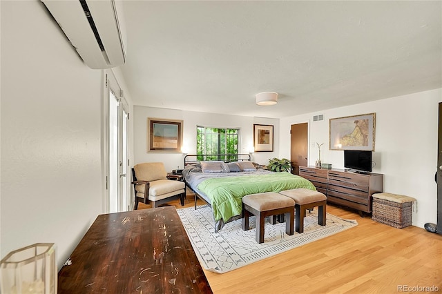 bedroom featuring a wall unit AC and light wood-type flooring