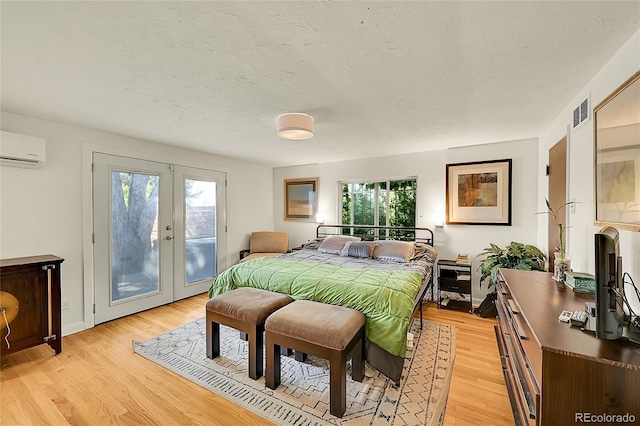 bedroom with access to exterior, a wall mounted AC, french doors, multiple windows, and a textured ceiling