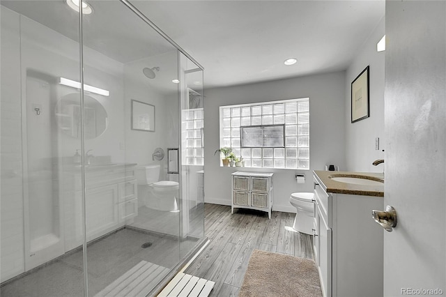 bathroom with toilet, vanity, a shower stall, wood finished floors, and recessed lighting