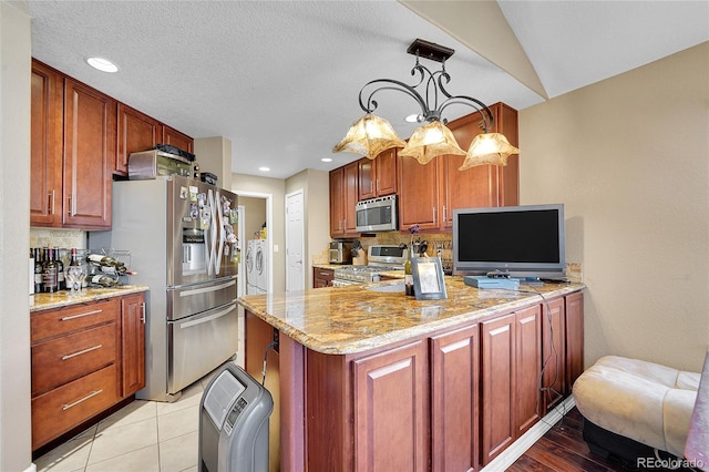 kitchen with pendant lighting, appliances with stainless steel finishes, light stone countertops, and backsplash