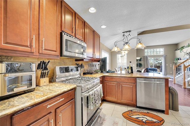 kitchen with tasteful backsplash, pendant lighting, light tile patterned flooring, and appliances with stainless steel finishes