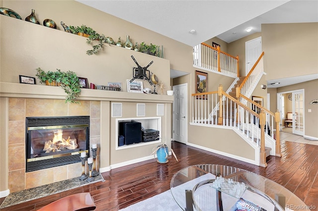 living room featuring hardwood / wood-style flooring, a fireplace, and a towering ceiling