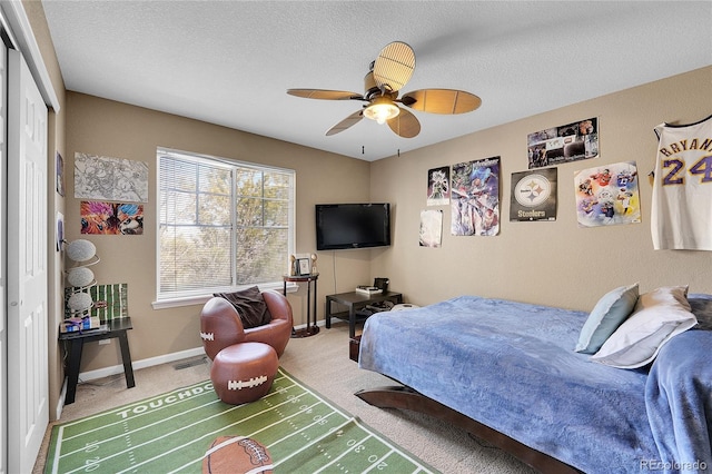 bedroom with ceiling fan, carpet floors, and a textured ceiling