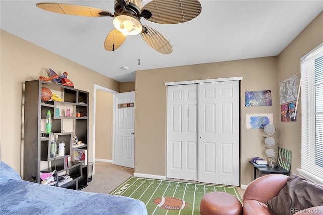 carpeted bedroom featuring ceiling fan and a closet