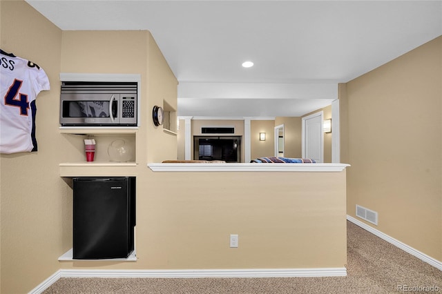 kitchen with fridge, carpet flooring, and kitchen peninsula