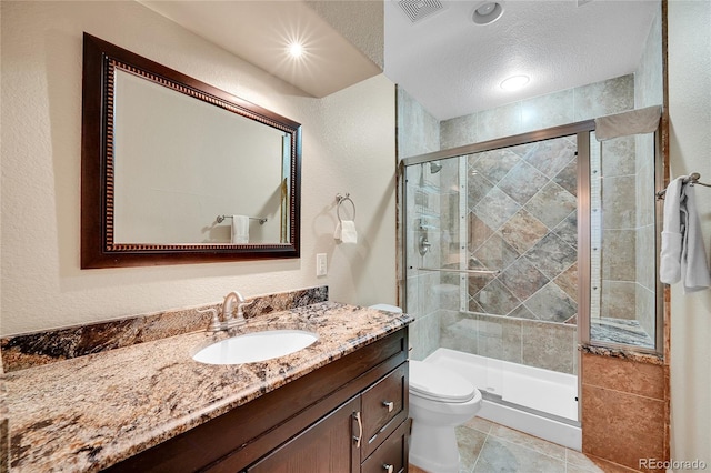 bathroom with vanity, toilet, a shower with shower door, and a textured ceiling