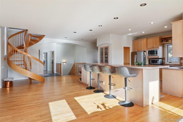 kitchen featuring light brown cabinets, stainless steel appliances, and light wood-type flooring