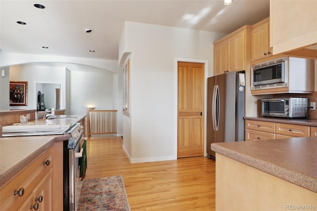 kitchen with light brown cabinetry, light wood-type flooring, stainless steel appliances, and sink