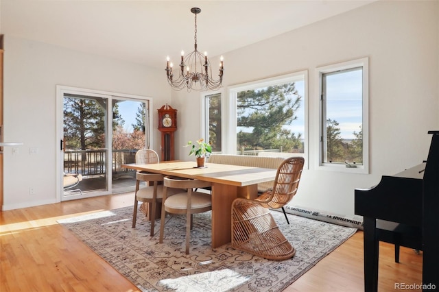 dining space with light hardwood / wood-style floors, a baseboard radiator, and a notable chandelier