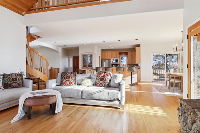 living room with a notable chandelier, light wood-type flooring, and high vaulted ceiling