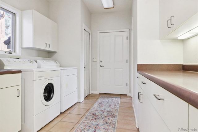 washroom with washer and dryer, light tile patterned floors, and cabinets