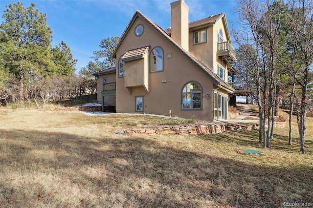 back of house with a yard and a balcony