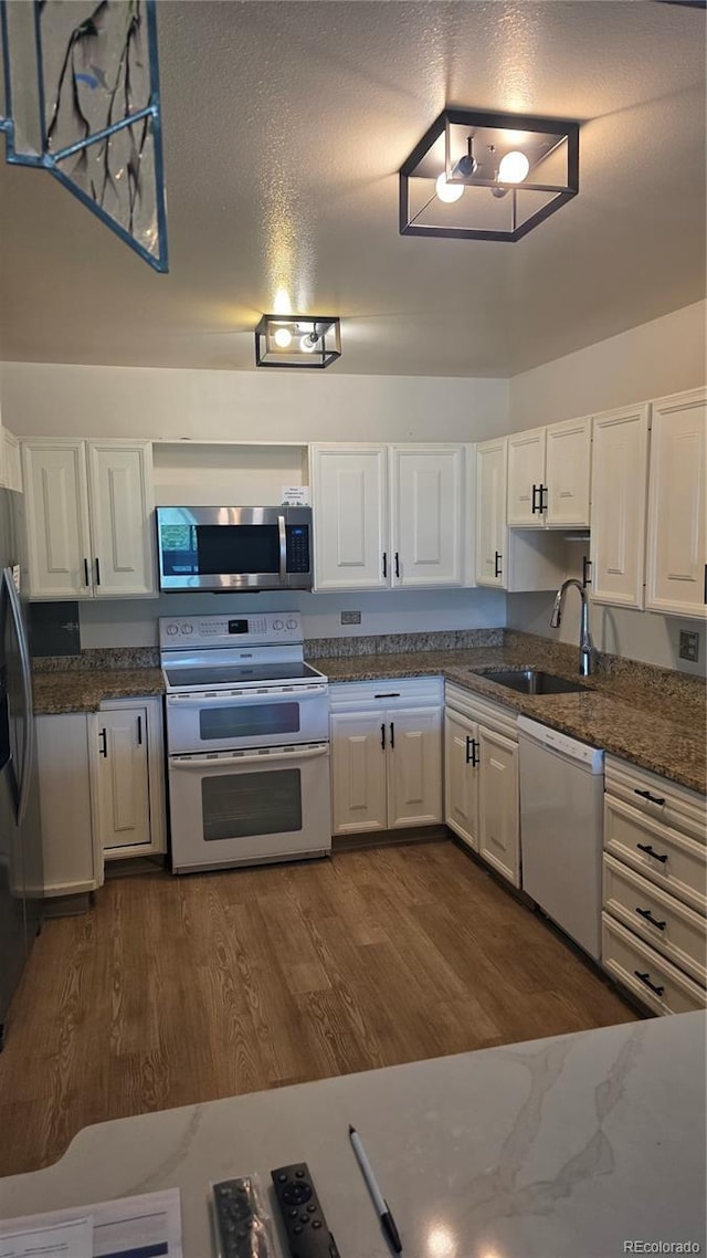775 S Alton Way Unit 3D, Denver, CO 80247 - kitchen featuring appliances with stainless steel finishes, white cabinets, dark wood finished floors, and dark stone countertops