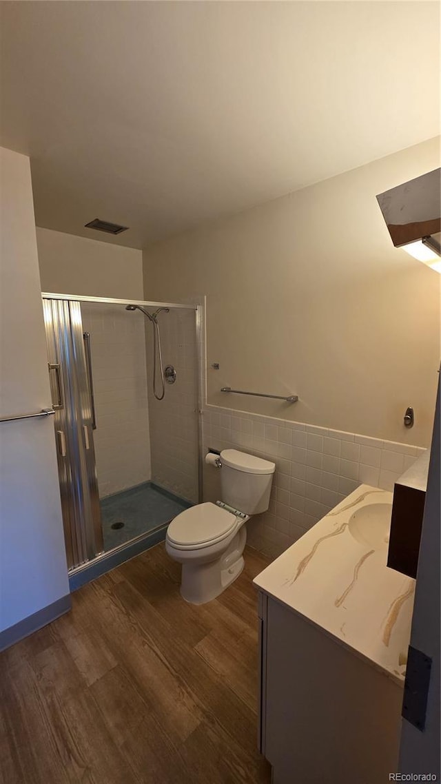 775 S Alton Way Unit 3D, Denver, CO 80247 - bathroom featuring vanity, wood finished floors, a stall shower, tile walls, and a wainscoted wall