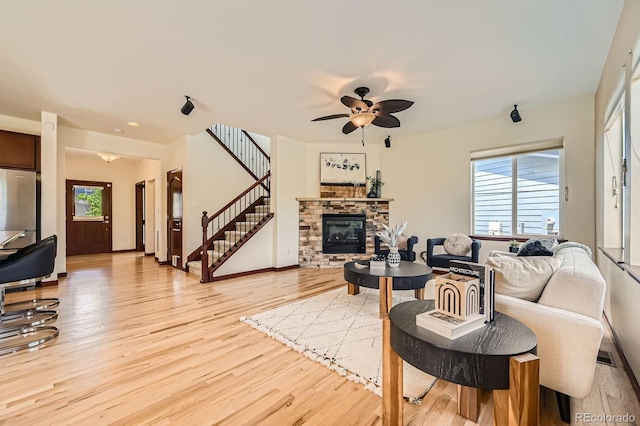 2150 Wagon Way, Louisville, CO 80027 - living room with light wood finished floors, a fireplace, a ceiling fan, stairway, and baseboards