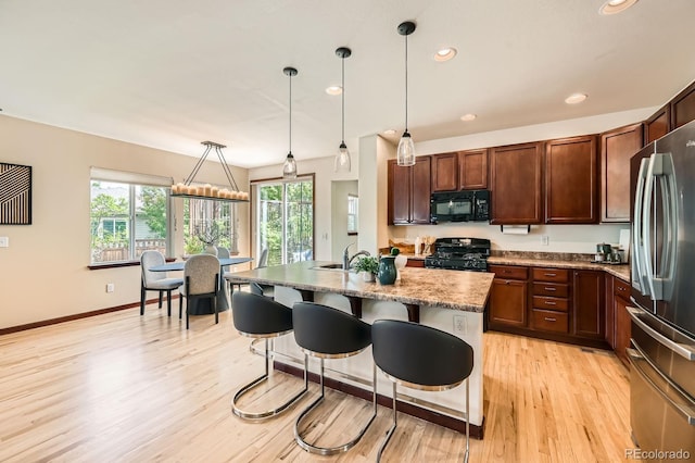 2150 Wagon Way, Louisville, CO 80027 - kitchen featuring black microwave, gas stove, freestanding refrigerator, light wood-type flooring, and a breakfast bar area