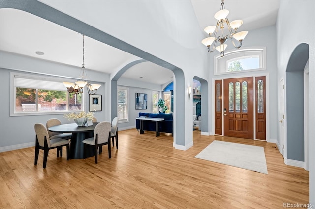 222 S Olive St, Denver, CO 80230 - entrance foyer featuring a chandelier, arched walkways, light wood-style flooring, and a towering ceiling