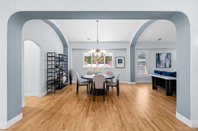 222 S Olive St, Denver, CO 80230 - dining area with light wood finished floors, arched walkways, and a chandelier