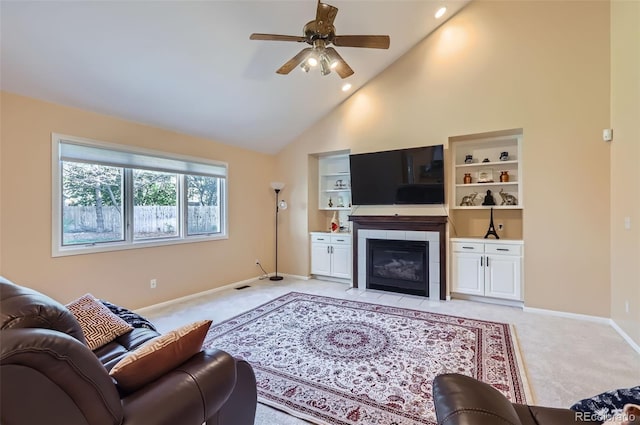 living area with light carpet, a ceiling fan, a tile fireplace, baseboards, and high vaulted ceiling