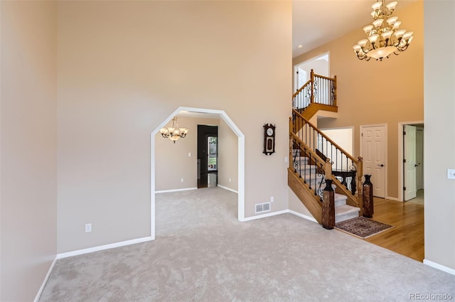 unfurnished room featuring a chandelier, carpet flooring, a high ceiling, stairs, and baseboards