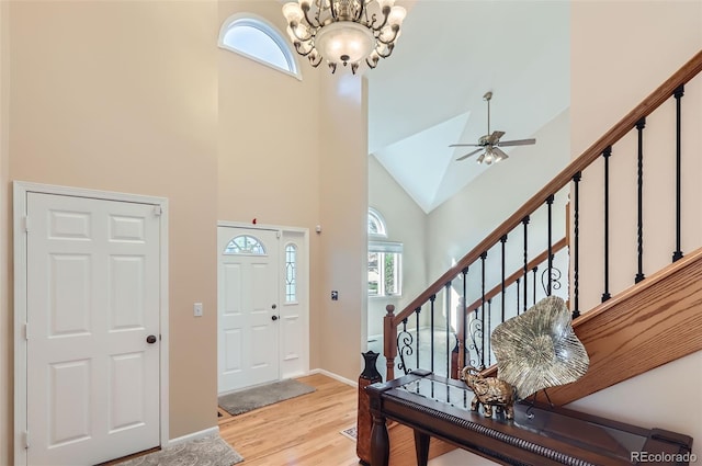 foyer with high vaulted ceiling, plenty of natural light, stairs, light wood-style flooring, and a ceiling fan