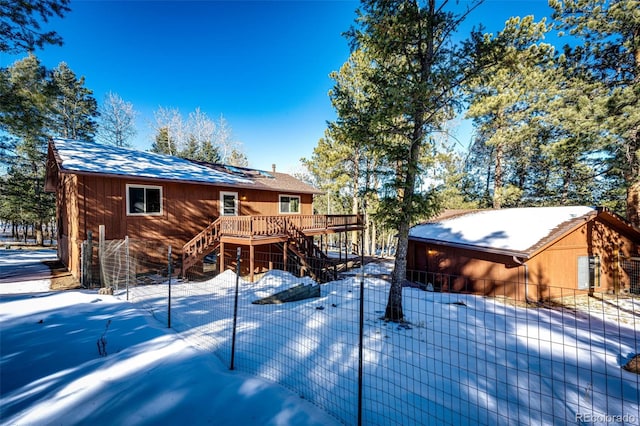 snow covered back of property featuring a wooden deck