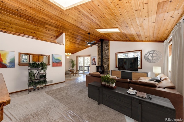 carpeted living room featuring wooden ceiling, a chandelier, vaulted ceiling with skylight, and a wood stove