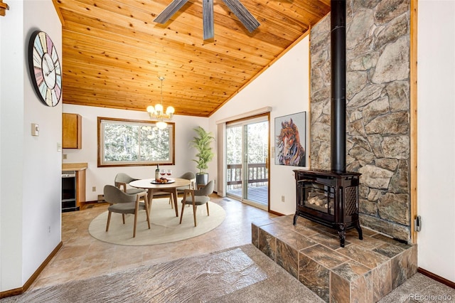 dining space with wood ceiling, ceiling fan with notable chandelier, high vaulted ceiling, and a wood stove