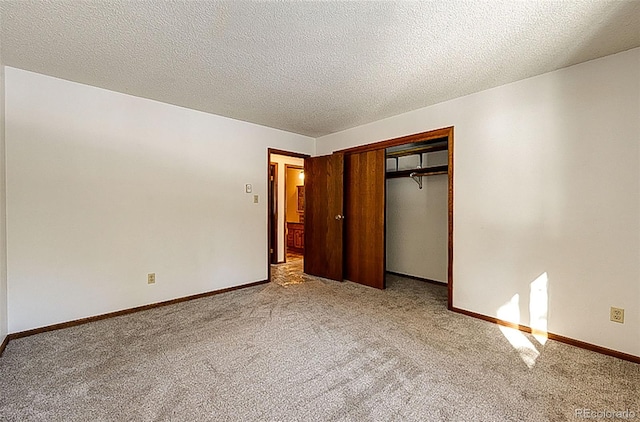 unfurnished bedroom with light colored carpet, a textured ceiling, and a closet