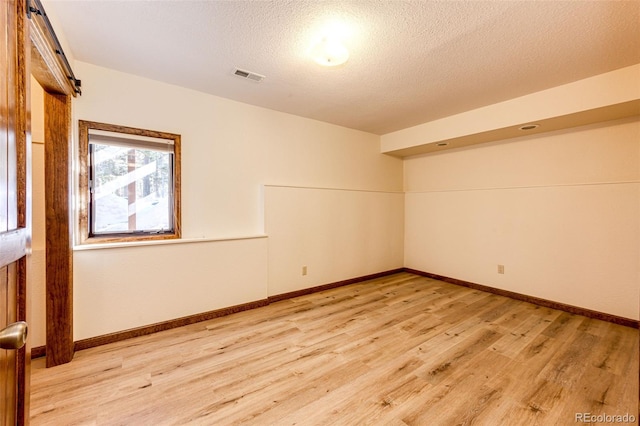 empty room with light hardwood / wood-style floors and a textured ceiling