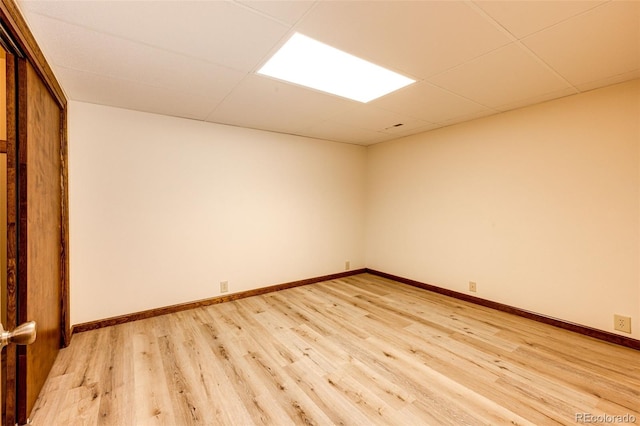 empty room featuring a paneled ceiling and light hardwood / wood-style floors