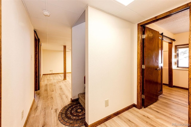 corridor featuring light hardwood / wood-style flooring and a barn door