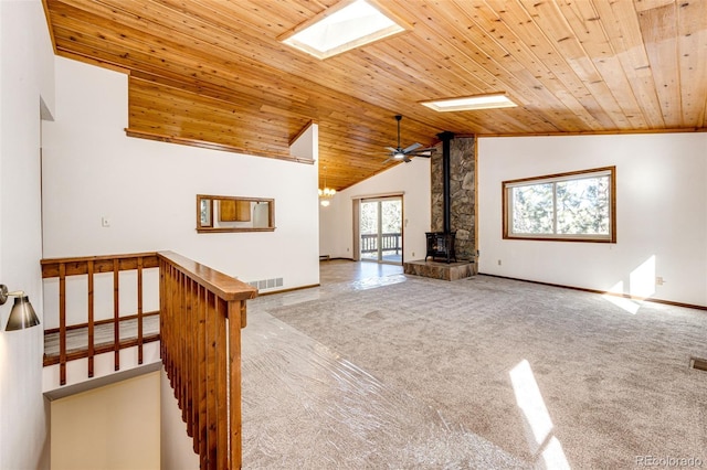 224 Yellow Pine Dr, Bailey, CO 80421 - unfurnished living room with a skylight, carpet, a wood stove, wood ceiling, and high vaulted ceiling
