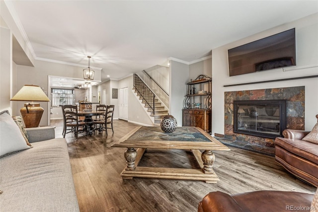 living area with baseboards, stairway, ornamental molding, a fireplace, and wood finished floors