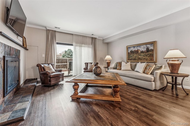 living room with visible vents, a tile fireplace, crown molding, and wood finished floors