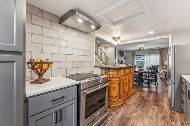 kitchen featuring premium range hood, dark wood-type flooring, gray cabinets, stainless steel appliances, and a peninsula