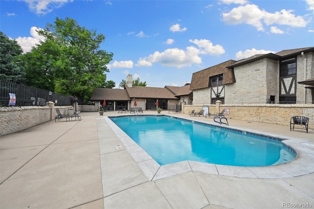 community pool with a patio area and fence