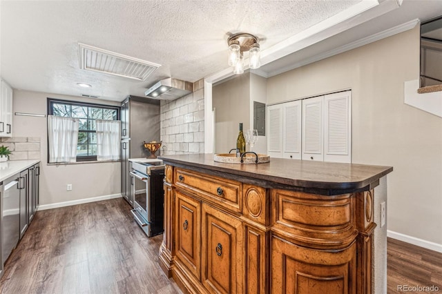 kitchen featuring dark countertops, a textured ceiling, decorative backsplash, and brown cabinetry