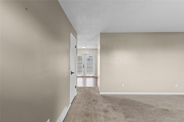 corridor featuring light colored carpet and a textured ceiling