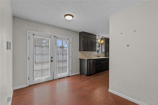 kitchen with french doors, tasteful backsplash, a textured ceiling, stainless steel dishwasher, and hardwood / wood-style floors