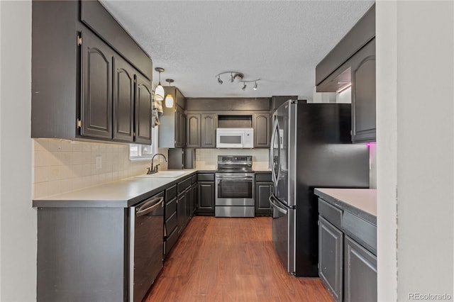 kitchen with dark hardwood / wood-style floors, sink, decorative backsplash, hanging light fixtures, and stainless steel appliances