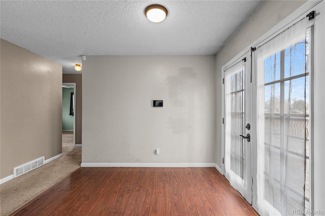 spare room with dark wood-type flooring, a textured ceiling, and french doors