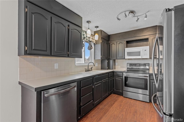 kitchen with dark wood-type flooring, sink, a textured ceiling, appliances with stainless steel finishes, and backsplash