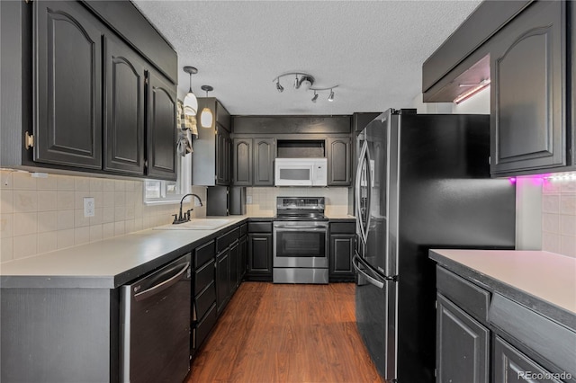 kitchen featuring sink, tasteful backsplash, appliances with stainless steel finishes, dark hardwood / wood-style floors, and pendant lighting