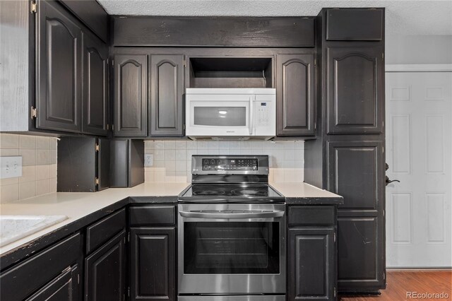 kitchen with electric stove, hardwood / wood-style floors, decorative backsplash, and a textured ceiling