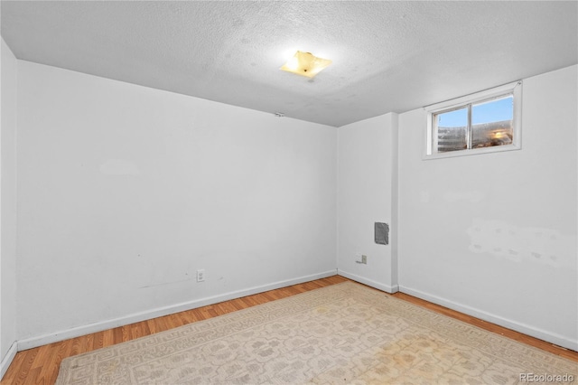 spare room with a textured ceiling and light wood-type flooring